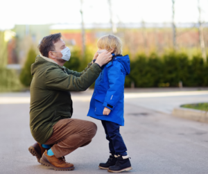 A father adjusts his child's mask